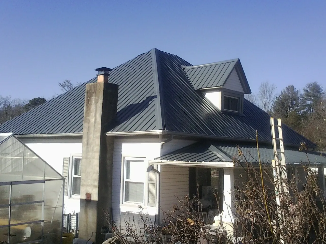 Dark blue standing seam metal roof on a white farmhouse with dormer — Slate & Tile Roof Repair by Roofing Brothers in Montgomery Creek