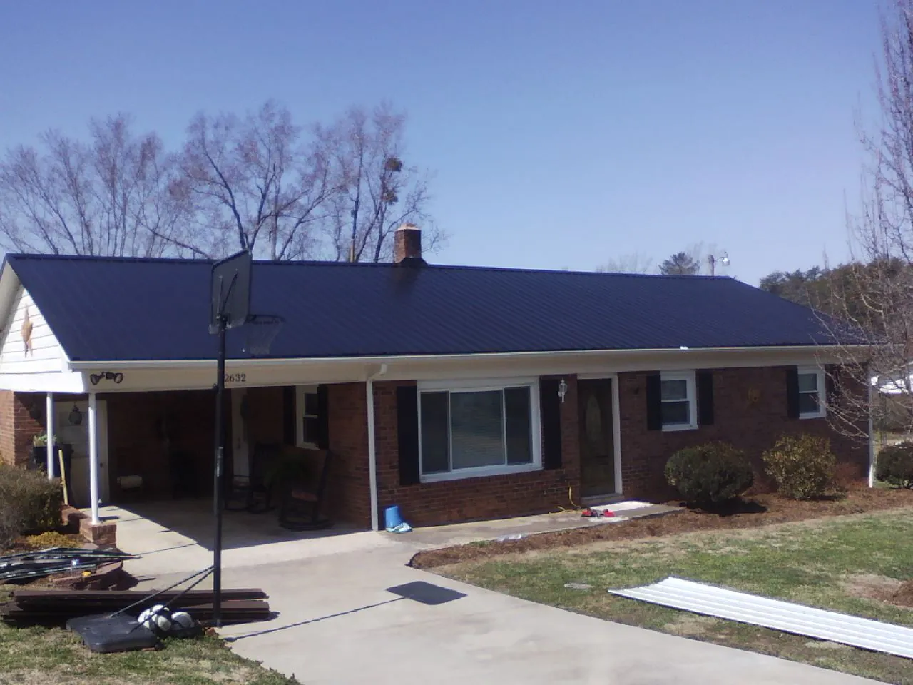 Finished dark blue metal roof on a brick ranch with a carport in Montgomery Creek