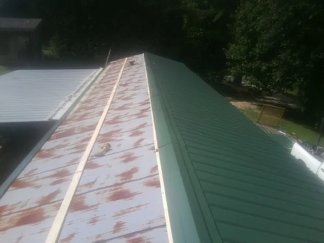 Old rusted panels beside newly installed green metal roofing — Wind Damage Roof Repair by Roofing Brothers in Montgomery Creek
