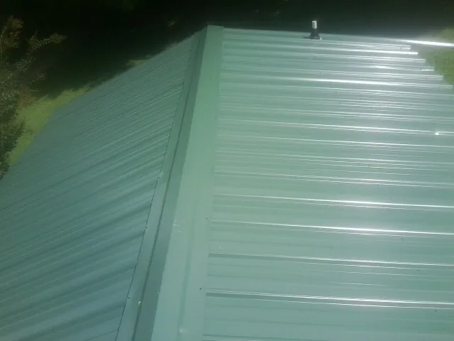New green metal panels meeting at the ridge of a roof — Flat Roof Repair work by our crew in Montgomery Creek
