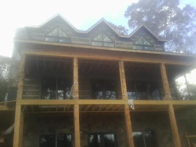 Dormers and porch framing on a large log home under construction — Roof Coating work by our crew in Montgomery Creek