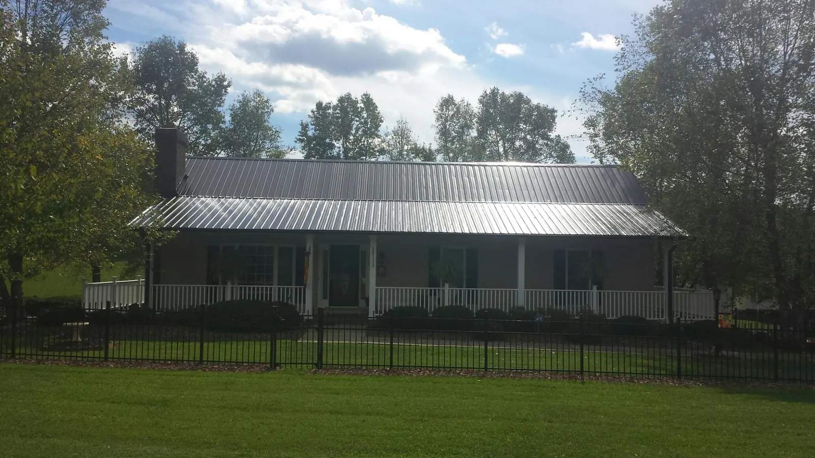 Gray metal roof on a brick ranch with a full width front porch — Gutter Guard Installation work by our crew in Montgomery Creek