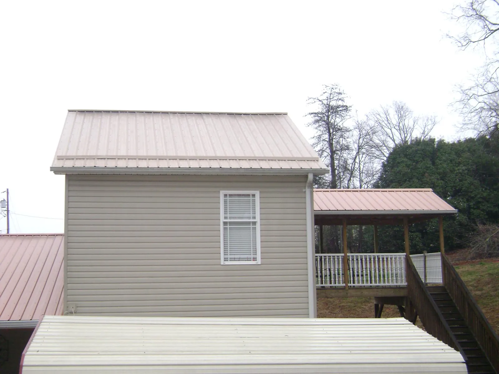 Tan metal roofs on a two story addition and attached porch, from a Roof Replacement job in Montgomery Creek